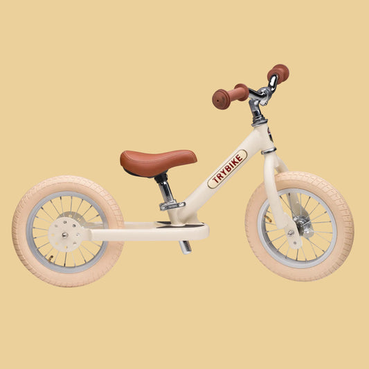 Children's balance bike with brown seat and handlebar grips on a white background