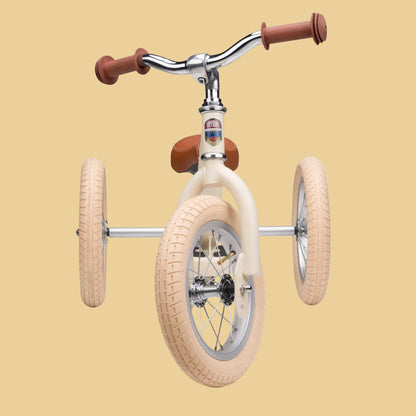 Children's tricycle with beige tires and brown handlebars on a white background